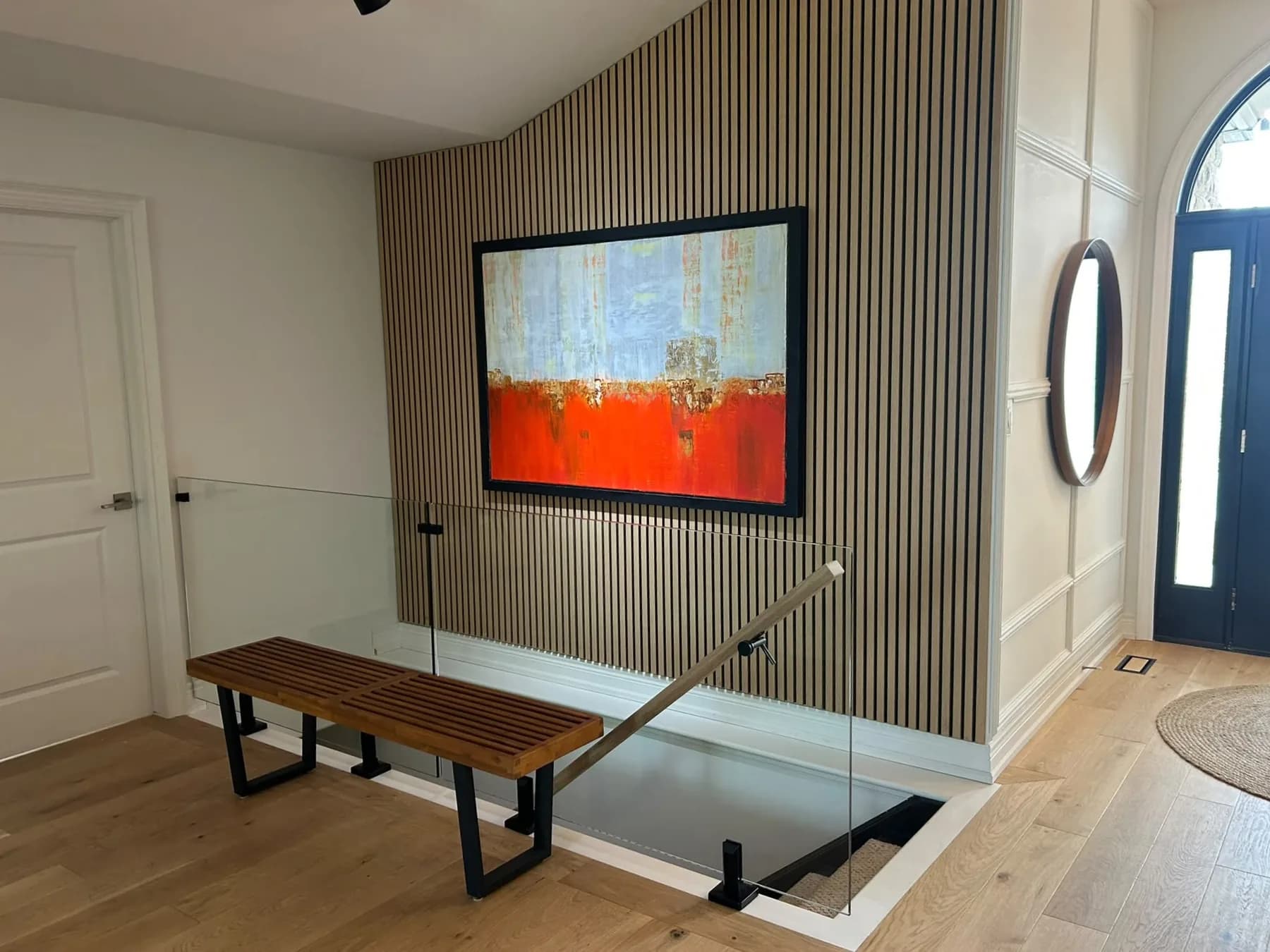 Frameless glass guard and floating oak handrail around an open stair in a Niagara home