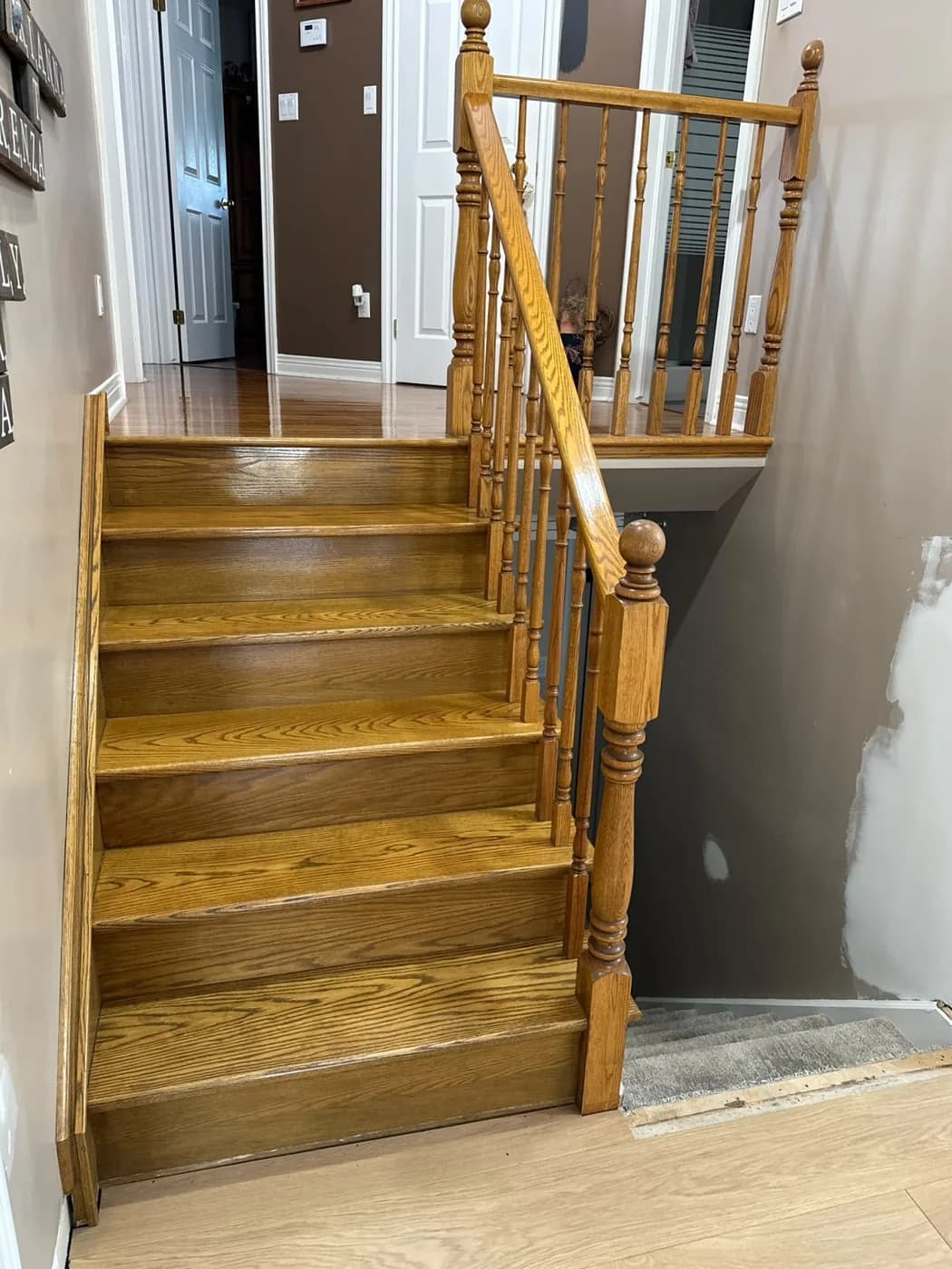 Staircase before recapping: golden-oak treads with original wood balusters